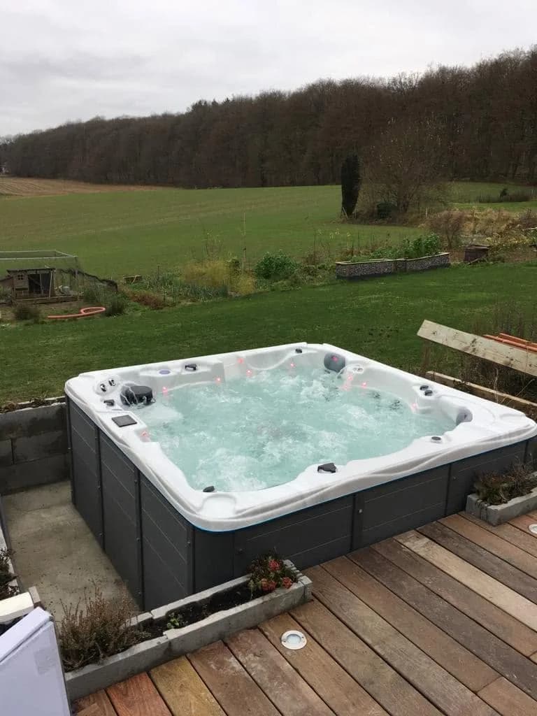 Installation d'un spa Vancouver à Henripont, sur une terrasse en bois, vue sur les prairies