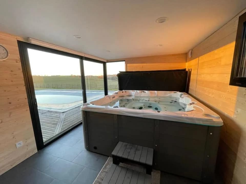 Installation d'un spa Vancouver à La Salvetat, en intérieur, baies vitrées sur la piscine