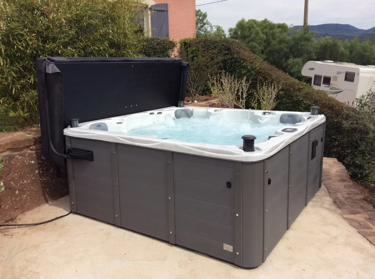 Installation d'un spa Vancouver à Le Bosc, sur une dalle dans un jardin, lève-couverture