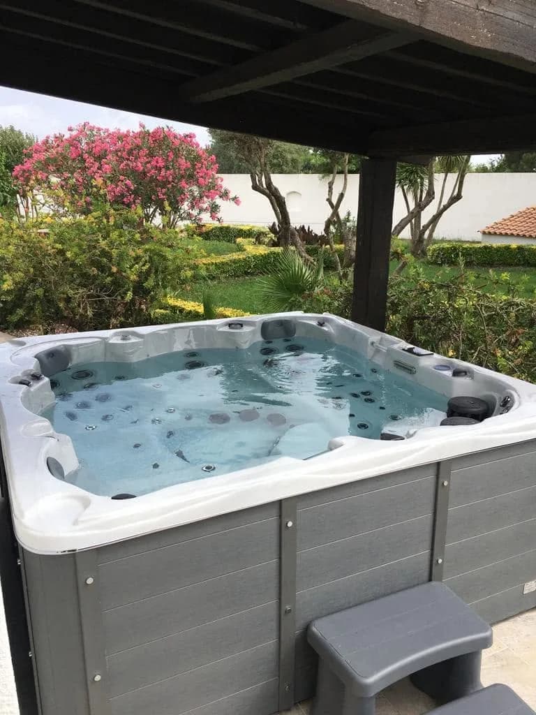 Installation d'un spa Vancouver à Lunel, sous un abri, piscine en arrière-plan