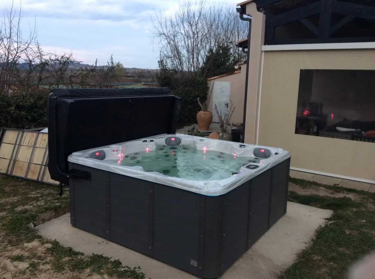 Installation d'un spa Vancouver à Maureillas-las-Illas, sur une dalle dans un jardin, lève-couverture