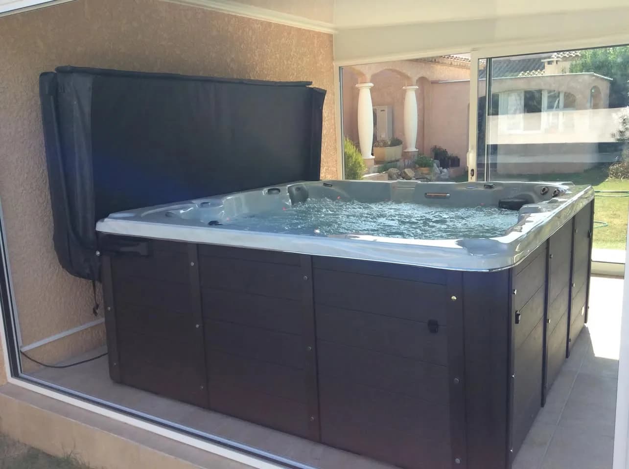 Installation d'un spa Vancouver à Névian, sur une terrasse couverte et vitrée, avec lève-couverture
