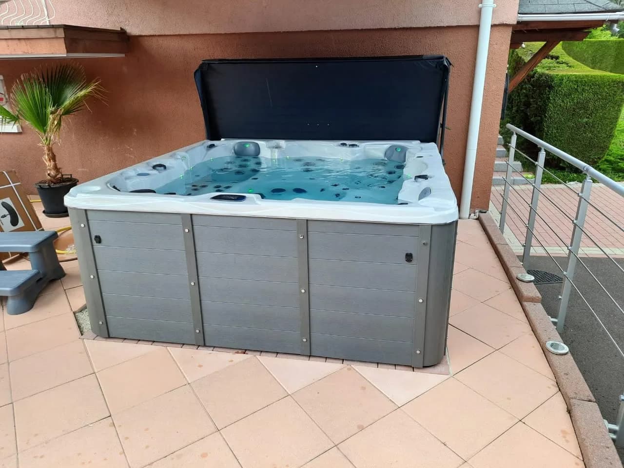 Installation d'un spa Vancouver à Plancher-Bas, sur une terrasse carrelée, lève-couverture