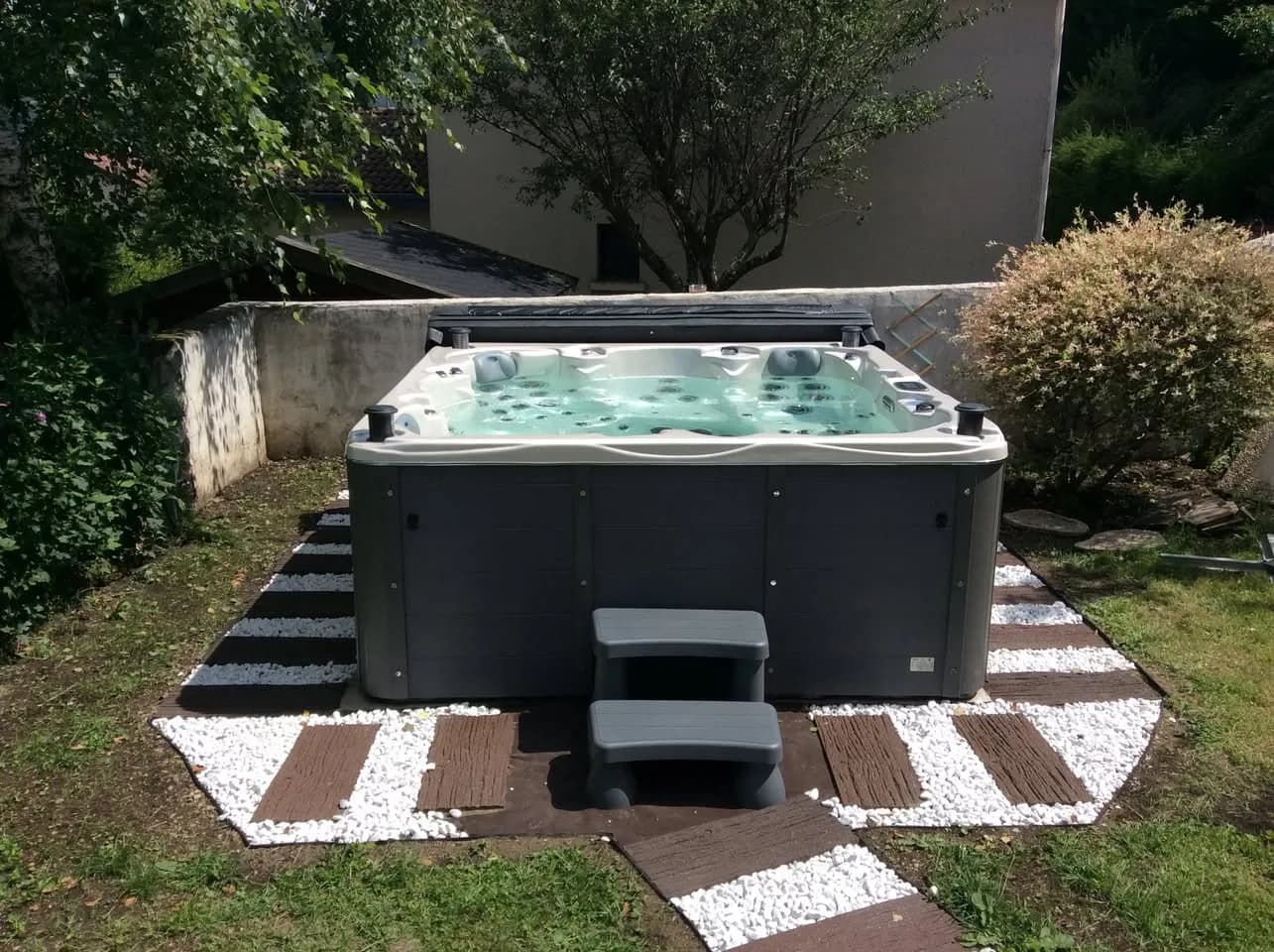 Installation d'un spa Vancouver à Saint-Étienne, sur la pelouse entouré de bandes de galets blancs