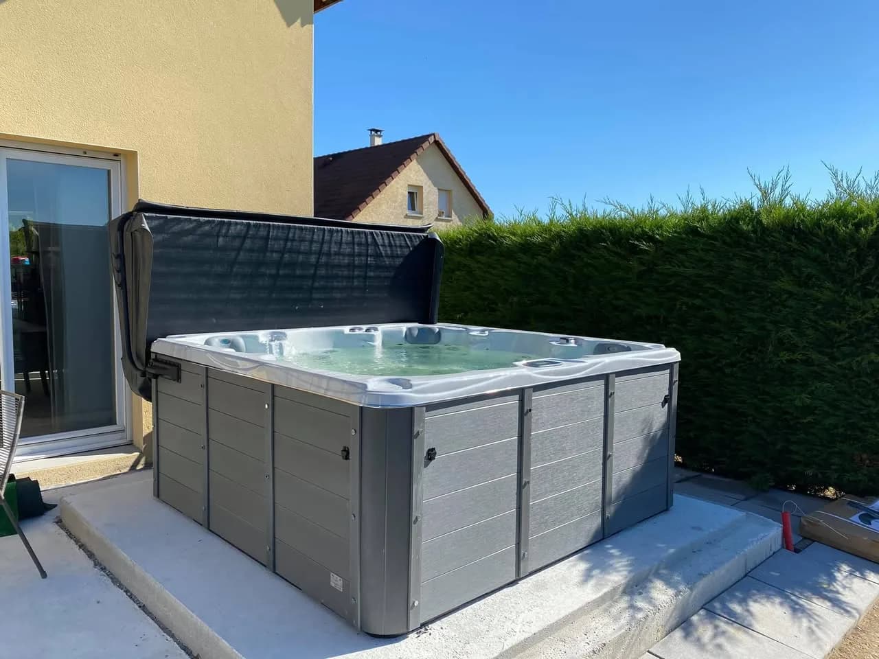 Installation d'un spa Vancouver à Saint-Germain-le-Châtelet, sur une dalle contre la maison, avec lève-couverture