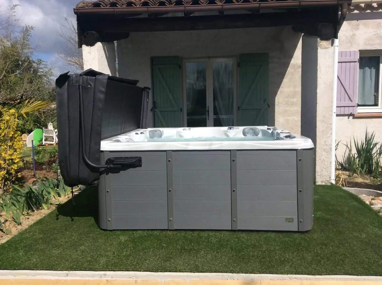 Installation d'un spa Vancouver à Soual, sur une pelouse synthétique, lève-couverture