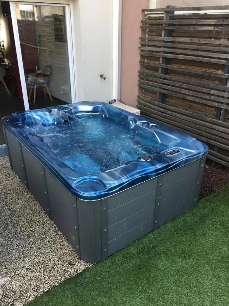Installation d'un spa Victoria Duel à Saint-Priest, sur un gazon synthétique, cuve bleue
