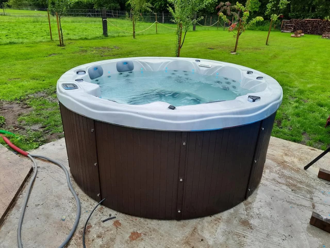 Installation d'un spa Yukon dans les Vosges, spa rond sur une dalle au milieu de la pelouse