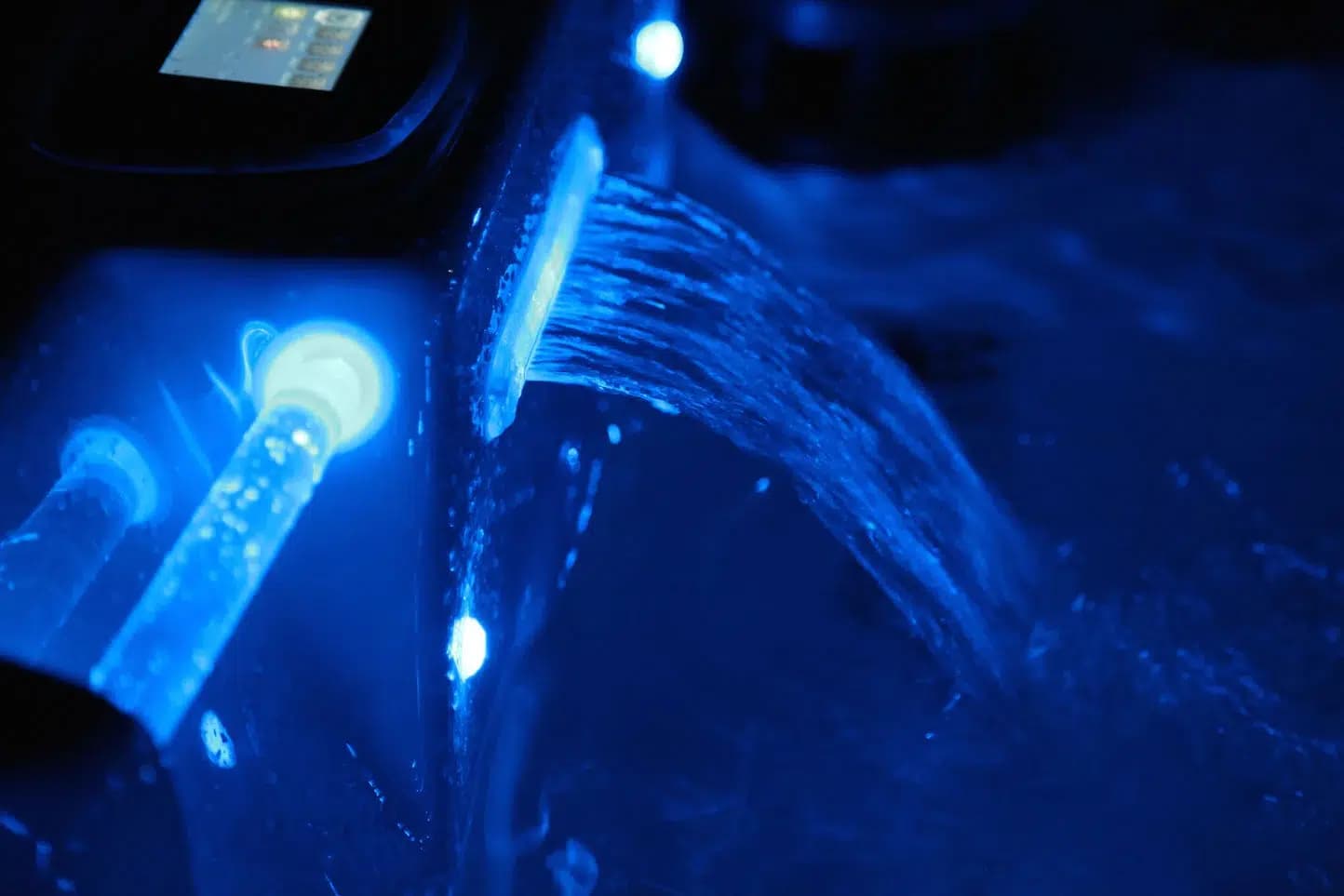 Cascade et jets d'un spa éclairés en bleu la nuit, eau en mouvement à la surface du bassin