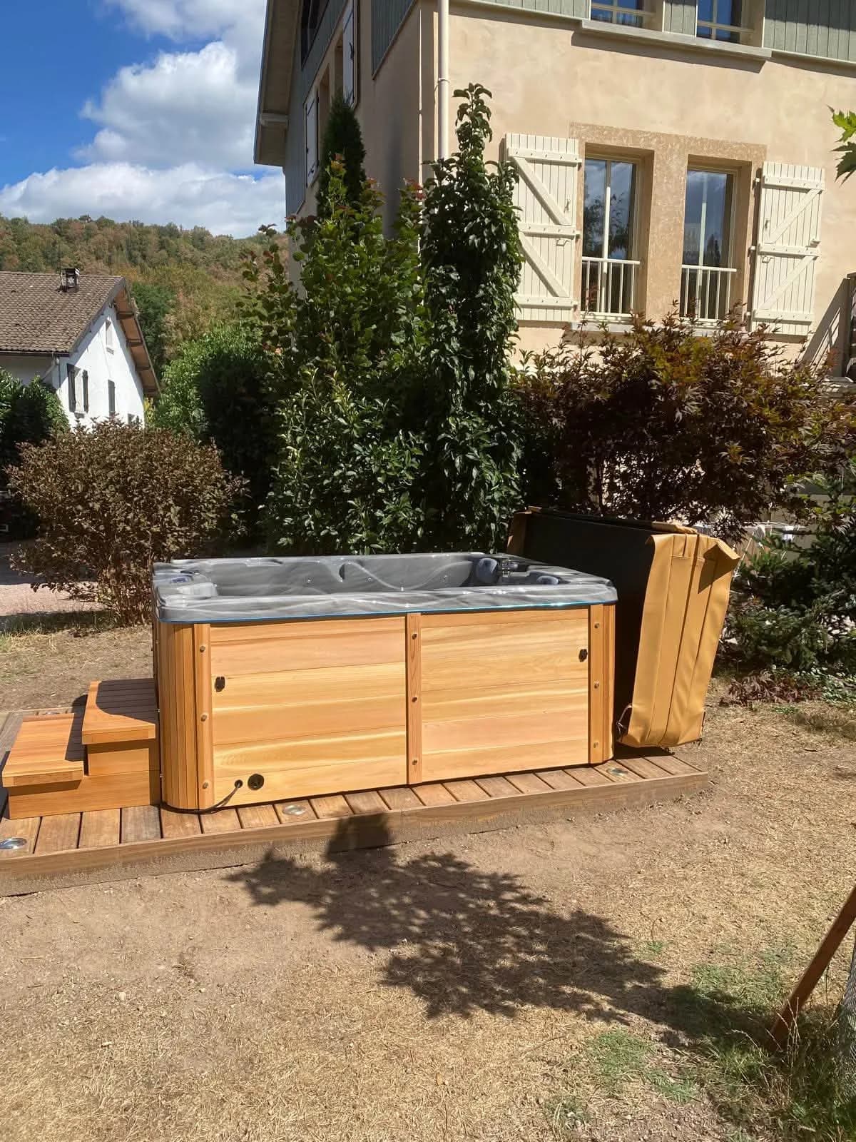 Spa Montana habillé de cèdre clair sur une terrasse en bois, collines des Vosges en arrière-plan