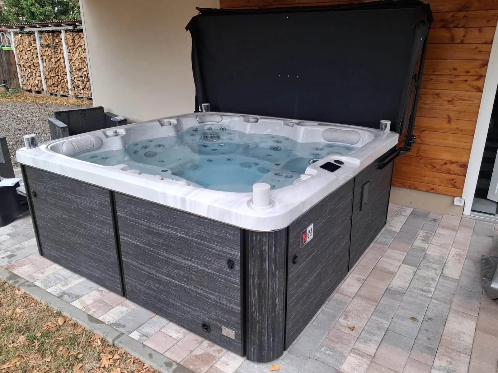 Spa Solveijg sur un pavage neuf, bûcher et bardage bois en arrière-plan